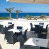Terrazza con tavoli vista mare e palme sullo sfondo.