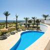 Piscina con lettini e palme vista mare.
