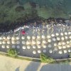 Spiaggia dall'alto con ombrelloni bianchi in fila.