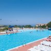 Piscina all'aperto con sdraio bianche e ombrelloni blu.