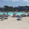 Piscina all'aperto con lettini blu e ombrelloni.