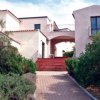 Una villa bianca con giardino e vialetto d'ingresso.