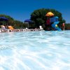 Una piscina con scivolo e sdraio.