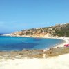 Una spiaggia con mare blu e ombrelloni rossi.