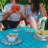 Coppia brinda con cocktail ad un tavolino all'aperto.