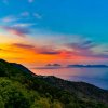 Tramonto sul mare con isole in lontananza. Verde collina sulla sinistra.