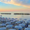Ombrelloni blu e bianchi al tramonto su una spiaggia.