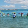 Persone in mare con tubi galleggianti colorati.