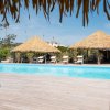 Piscina con tettoie di paglia e lettini.