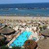 Piscina affollata vicino a una spiaggia sabbiosa.