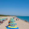 Spiaggia con ombrelloni e bagnanti vicino al mare.