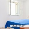 Letto matrimoniale con coperta blu e lampada da tavolo.