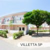 Edificio residenziale con due piani, balconi e cespugli.