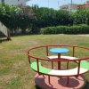 Parco giochi con scivolo giallo e giostra rotonda su erba.