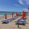 Spiaggia con ombrelloni e sdraio azzurri allineati a destra.