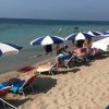 Lettini e ombrelloni bianchi e blu su una spiaggia.