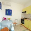 Una cucina compatta con armadietti gialli e un tavolo con tovaglia a righe blu.