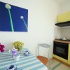 Una cucina con tavolo coperto da tovaglia a righe, fiori rosa e un quadro con fiori verdi.