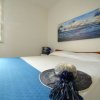 Letto matrimoniale con copriletto blu, un quadro del mare e un cappello di paglia posato sul letto.